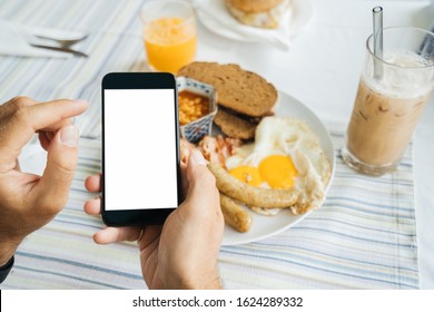 Mock up, black Smartphone in hand on a light food background. Calorie counting, weight tracking, and calorie foods. American breakfast: Fried eggs with sausages, tomatoes, bacon, and toasted bread. - Powered by Shutterstock