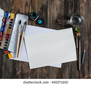 Mock up. Creative space. Artistic work tools on dark wooden table: watercolor, paintbrushes and water. - Powered by Shutterstock