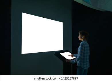 Mock Up, Futuristic, Template And Education Concept. Woman Using Electronic Kiosk And Looking At White Blank Large Interactive Wall Display In Dark Room Of Modern Technology Museum - Mockup Image