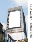 Mock up white vertical large LED display billboard on tower building with blue sky background .clipping path for mockup