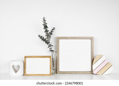 Mock up wood frames with rustic Valentines Day wooden heart decor, eucalyptus branch and candle holder. White shelf against a white wall. Copy space. - Powered by Shutterstock