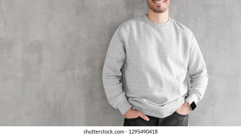 Mock up of young man body in empty sweatshirt isolated on textured gray wall background. No face photo
