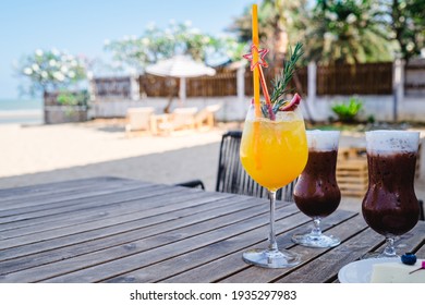 Mocktails Are On The Table At The Beach. It Is Consists Of Mango, Passion Fruit, Syrup, Soda, And Ice. This Menu Tastes Sweet, Tingle, And Sour. People Drink These Beverages And Spent Time Relaxing.