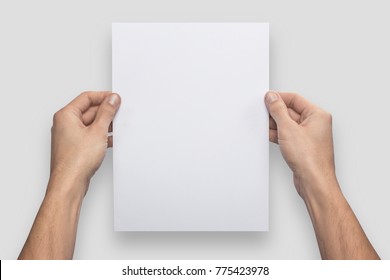 Mockup A4 Letter Vertical Empty Blank White Holds The Man In His Hand. Isolated On A Gray Background