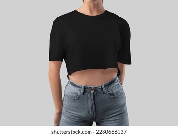 Mockup of black crop top on girl in gray jeans, blank t-shirt canvas bella, for design, branding, front view. Fashion clothes template, shirt isolated on background. Women's textured apparel close-up