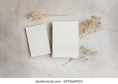 Mockup of blank cards 5x7 and 4x6 with dried flowers on bright concrete background; invitations sample design