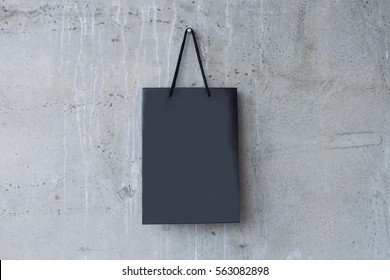 Mock-up Of Blank Craft Package, Mock Up Of Black Paper Shopping Bag With Handles On The Cement Or Concrete Background.