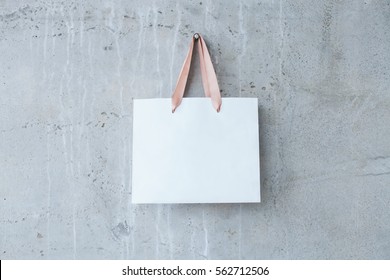 Mock-up Of Blank Craft Package, Mockup Of White Paper Shopping Bag With Handles On The Concrete Background.