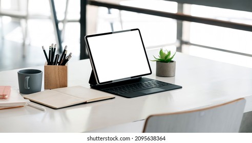 Mockup blank screen portable tablet with magic keyboard on white table in modern office room. - Powered by Shutterstock