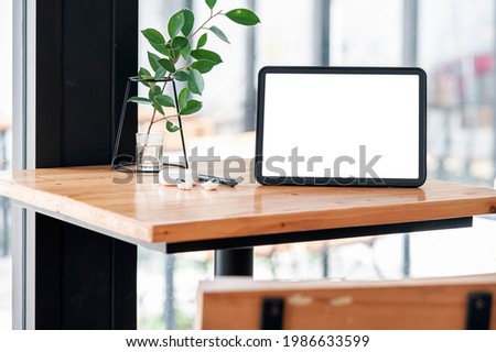 Mockup blank screen tablet and gadget on wooden table.
