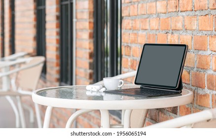 Mockup Blank Screen Tablet With Keyboard On The Table Outside Cafe Room.