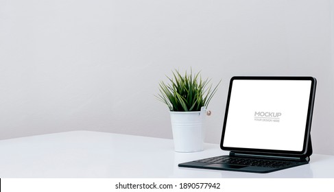Mockup blank screen tablet with magic keyboard on white table in white room, copy space.