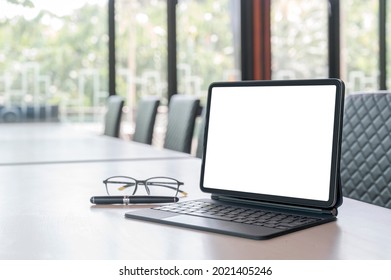 Mockup Blank Screen Tablet With Magic Keyboard On Wooden Table In Meeting Room.