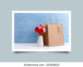 Mockup of blank shopping bags. Gerbera flowers in vase. Brown craft package. Concept for sales or discounts. Blue wooden rustic board. Photo frame design with shadow. - Powered by Shutterstock