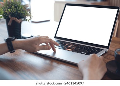 Mockup blank white screen laptop computer. Business woman using and searching the information on laptop with empty screen on wooden table in modern loft cafe. Back view, template for online marketing