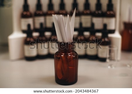 Mockup brown glass bottle with blotter paper for testing smell of essential oil and fragrance oil. Perfume tester paper strips.