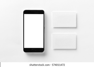Mockup of cellphone with blank screen and business cards isolated at white paper.