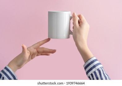 Mockup Ceramic White Coffe Cup Or Mug In Female Hands On Pink Background With Copy Space. Blank Template For Your Design, Branding, Business. Woman In Striped Shirt Casual Style. Real Photo.