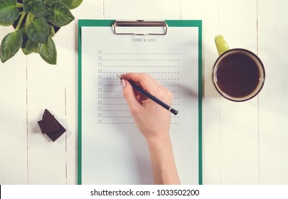 Mockup for check list, empty note paper with pen and coffee cup on light background. Office, writer or study concept. female hand with a pencil