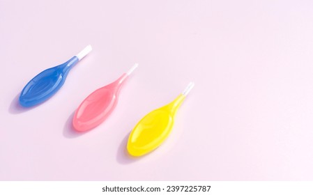 Cepillos dentales coloridos de enrejado entre cordones de goma de dientes sobre fondo rosado, escopeta de dientes de cepillo interdental con suaves cerdas, herramienta de limpieza dental oral. Copiar espacio para texto, plano horizontal