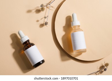 Mockup cosmetic bottles with a dropper on a beige background with bright sunlight and hard shadows. The concept of natural cosmetics, natural essential oil