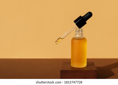 Mockup of cosmetic oil bottle with dropper removed on wooden stand. Horizontal monochrome brown banner, copy space. Natural lotion, essence, serum, emulsion. Frosted amber vial, black cap, front view