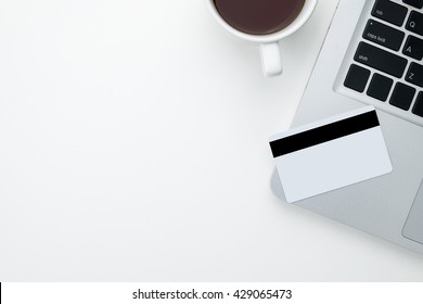 The Mockup Credit Card Is Put On A Laptop On White Table With Coffee Cup. Top View Copy Space.