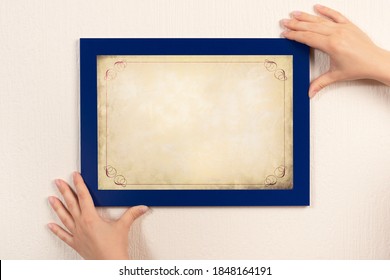 Mockup Diploma. Woman Hanging Photo Frame Mockup On Wall. OLD Grunge Certificate With Vintage Ornamental Frame Mockup