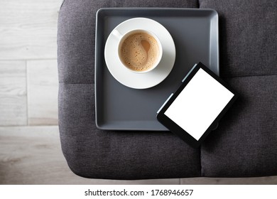 Mockup Ebook On Soft Modern Armchair With Blank White Screen, To Replace Your Design. Cup Of Coffee For Cozy Atmosphere Reading. Paste Your Book Cover Here