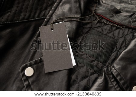 Mockup - an empty label for text on a drawstring lies on a black leather jacket with a metal zipper.