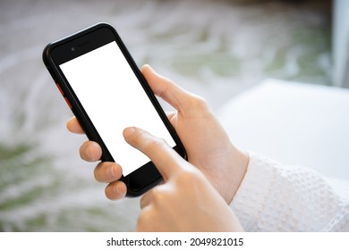 Mockup empty white screen smartphone isolated with clipping path. Unrecognizable Asian young woman in bathrobe or shower suit using a smartphone in bedroom for social media or social network. - Powered by Shutterstock