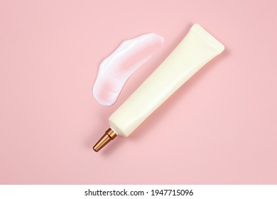 Mockup Of Face And Eye Cream Squeeze Cosmetic Tube With Long Nozzle And Bronze Screw Cap And Big Smear Of Moisturizer On Pink Background. Natural Organic Spa Cosmetics Concept, Flatlay, Top View.