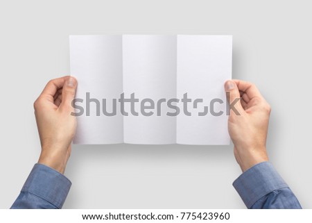 Mockup flaeth folded three times empty blank white holds the man in his hand in shirt. Isolated on a gray background