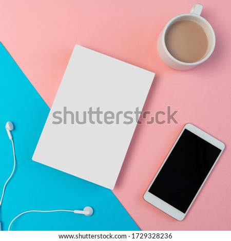 Mockup Flat lay composition with smartphone, headphones, notepad and cup of coffee on a blue and pink background.