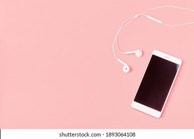 Mockup And Flat Lay Template With White Color Phone Smartphone And Headphones On Pink Background With Copy Space. Studio Shot Concept About Communication And Music.