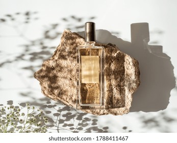 Mockup geometric shape stone podium with glass perfume bottle top view. Stone shape with gypsophila flowers shades over white background. Flat lay. Can use as perfume and cosmetic mock up