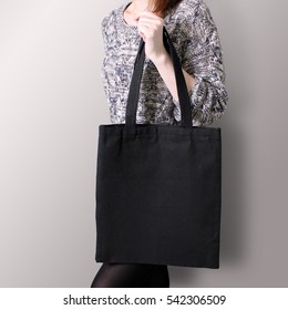 Mock-up. Girl is holding black cotton tote bag. Handmade eco shopping for girls.