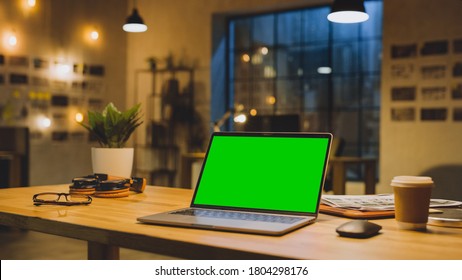 Mock-up Green Screen Stanting On The Desktop. In The Background Stylish Modern Office Studio In The Evening With Big Cityscape Window