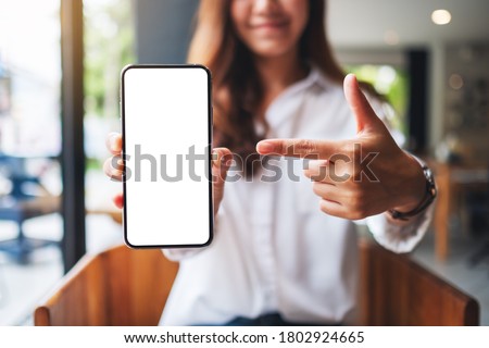 Mockup image of a beautiful woman pointing finger at a mobile phone with blank white screen 