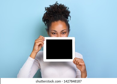 Mockup Image Of Black Empty Blank Screen Of Ipad In The Female Hand, Peeking From Behind Tablet Over Blue Background