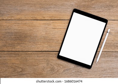 Mockup image of black tablet computer pc with blank white screen with pencil isolated on wood table background. Top view. Flat lay. Clipping path. Copy space for text.