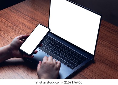 Mockup image with blank screen of computer and smartphone. Background for advertising text. Woman using smartphone at desk. Space for design.
