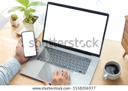 mockup image blank screen computer,cell phone with white background for advertising text,hand man using laptop texting mobile contact business search information on desk in office.marketing and design