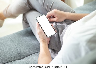 Mockup image blank white screen cell phone.man hand holding texting using mobile on sofa at home office.background empty space for advertise text.people contact marketing business,technology 