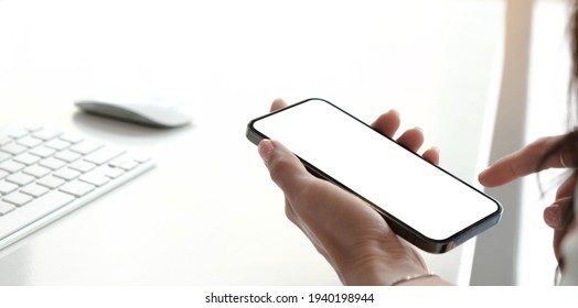 Mockup Image Blank White Screen Cell Phone.women Hand Holding Texting Using Mobile On Desk At Home Office. 