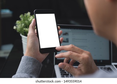 Mockup Image, Business Man Hand Holding Blank Screen Mobile Smart Phone, Working On Laptop Computer With Digital Tablet On Table In Modern Office For Website Or Application Design, Over Shoulder View