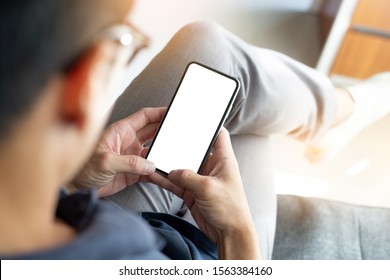 mockup image cell phone blank white screen for text.sit enjoy relax on sofa using mobile.hand holding texting message chatting with friend.concept for modern communication in the business financial