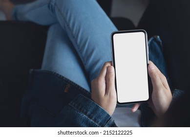 Mockup Image Of Cell Phone. Woman Hand Holding And Using Blank White Screen Mobile Phone. Female Hipster In Blue Jeans Using And Looking At Empty Mobile Smartphone Screen, Mock Up Template