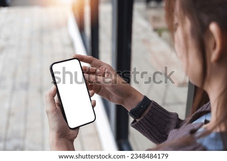 Mockup image of closeup woman hand holding mobile phone with blank white smartphone screen at the outdoor.