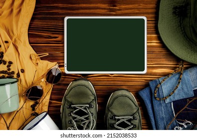 Mockup Image Of Digital Tablet. Surrounded By Camping Stuff And Cloth. Planning For Travel Outdoors. Flat Lay, Top View